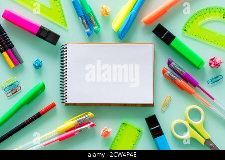 Schul- und Büroartikel, farbige Stifte, Heftklammern, Filzstifte, Set Quadrate, ein leeres Notizbuch für den eigenen Text in der Mitte. Stockfoto