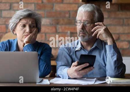 Gestresste ältere Männer und Frauen haben Probleme, online zu bezahlen Stockfoto