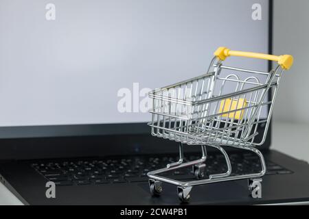 Warenkorb auf Laptop-Tastatur. Weißer Bildschirm mit Platz für Text. Konzept von Online-Shopping und Online-Shops Stockfoto