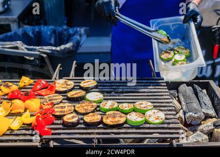 Der Koch kocht Gemüse auf dem Grill. Zuccini-Scheiben, Auberginen, Pfeffer auf offenem Feuer geröstet Stockfoto