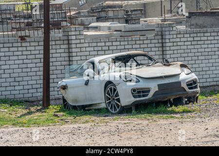 Verbranntes weißes fremdes Auto nahe der weißen Ziegelmauer. Feuerwehrauto. Stockfoto