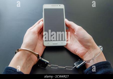 Verhaftete Frau in Handschellen, während sie das Smartphone hielt Stockfoto