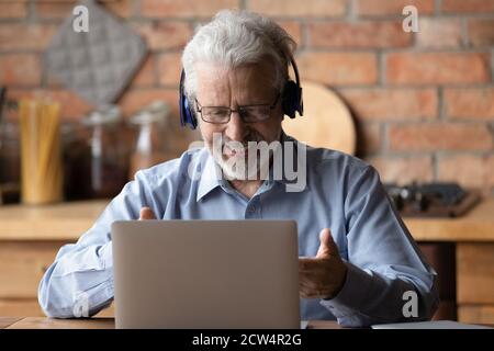 Lächelnder älterer Mann spricht bei einem Videoanruf auf dem Laptop Stockfoto