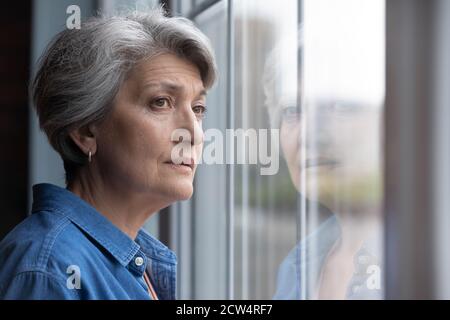 Traurige ältere Frau schauen im Fenster fehlt oder denken Stockfoto