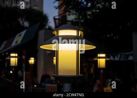 Lamppost in einem Café auf der Straße gelb beleuchtet Der Abend Nahaufnahme Stockfoto