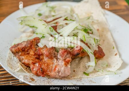 Fleischspieße auf Pita-Brot mit Zwiebeln in der Nähe Stockfoto