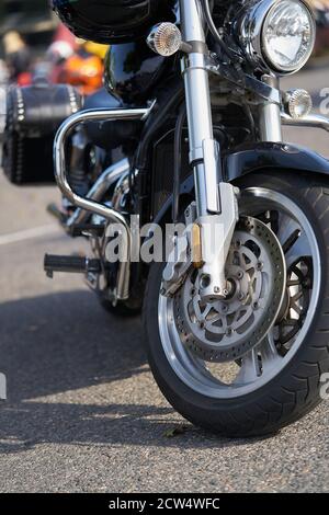 Chrome Motorrad. Lager. Seitenansicht des neuen schwarzen Motorrads mit Chrom-Details und Kleidung des Motorradfahrers darauf liegend. Chrome Details Motorrad Ref Stockfoto