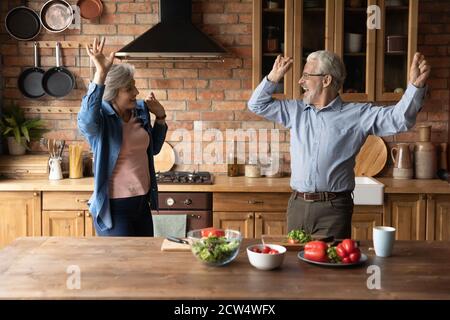 Aufgeregt gesundes Senior-Paar tanzen Kochen zusammen Stockfoto