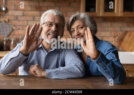 Lächelnder reifer Ehemann und Ehefrau winken im Videoanruf Stockfoto