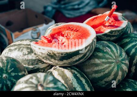 Wassermelonenmarkt. Viele große Wassermelonen und ein geschnittenes Stück Wassermelone Stockfoto