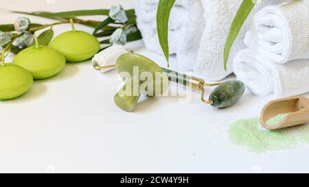 Spa chinesische Gesichtspflegemittel. Jadestein, Jadewalze, Eukalyptussalz und Kerzen auf weißem Hintergrund. Anti-Aging Hautpflege. Stockfoto