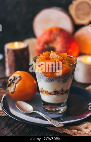 Köstliches Frühstück: chia-Samenpudding und Kakimmon in einem Glas auf dem Tisch. Vertikal. Stockfoto