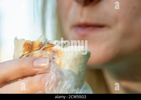 Das Mädchen isst Shawarma an einem sonnigen Tag. Nahaufnahme Lippen von Mädchen und Shawarma. Stockfoto