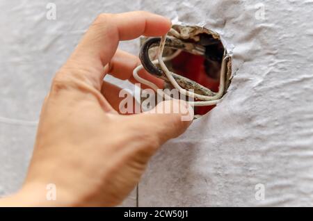 Elektriker Hände, Steckdose Installation mit einem Schraubendreher in der Wand, die Drähte von der Steckdose Stockfoto