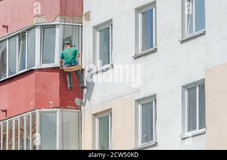 Industriekletterer versiegelt Risse in der Wand eines mehrstöckigen Gebäude im Freien Stockfoto