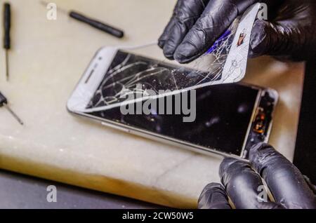 Techniker oder Ingenieur Öffnung gebrochen Smartphone zur Reparatur oder ersetzen Sie das neue Teil auf Schreibtisch Stockfoto