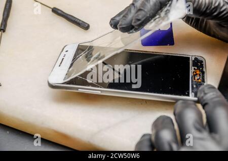 Techniker oder Ingenieur Öffnung gebrochen Smartphone zur Reparatur oder ersetzen Sie das neue Teil auf Schreibtisch Stockfoto