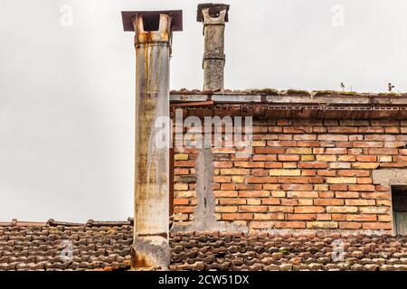 Alte Rauchfachs von gefährlichem Asbest auf dem Ziegeldach des Zerbröckelens Haus Stockfoto