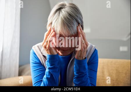 Ältere Frau, Die An Stress Oder Kopfschmerzen In Der Home Holding Leidet Kopf In Schmerzen Stockfoto