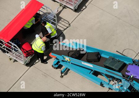 Gepäckabfertiger, die Koffer an einem Kreuzfahrtterminal in Southampton auf ein Förderband verladen. Stockfoto