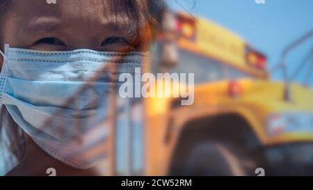 Composite-Bild von Ihnen Mädchen trägt Gesichtsmaske vor Von gelben Schulbus mit beunruhigten Blick auf ihr Gesicht Während der COVID-19 Pandemie Stockfoto