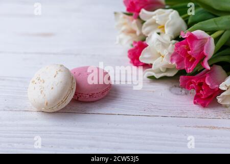 Tulpen mit Makronen auf weißem Holzhintergrund. Rustikale Tulpen. Stockfoto