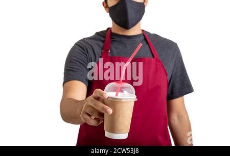 Kaffee zu gehen im Café Shop Coronavirus Days Konzept. Barista trägt eine Gesichtsschutzmaske, in der der Take Away Pappbecher vor weißem Hintergrund isoliert gehalten wird. Stockfoto