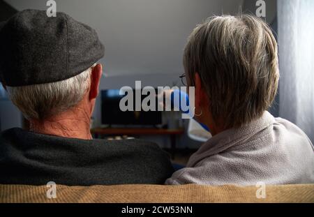 Rückansicht Des Älteren Ehepaares, Das Auf Dem Sofa Zu Hause Sitzt Gemeinsam Fernsehen Stockfoto