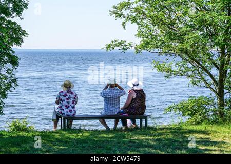 Ein zwei alte Frauen und ein Mann sitzen auf einem Bank am Meer und Blick in die Ferne Stockfoto