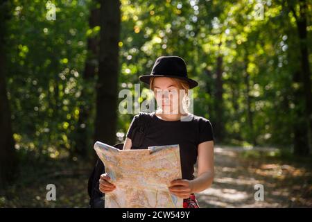 Junge kaukasische Frau in Hut Blick auf geographische Karte Stockfoto
