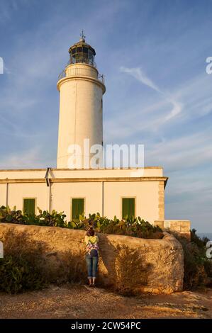 Weibliche Wanderin, die den Leuchtturm von La Mola an einem klaren Tag gegen den blauen Himmel fotografiert (La Mola, Formentera, Pityusen, Balearen, Spanien) Stockfoto