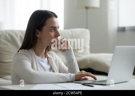 Nachdenkliche junge Frau arbeiten auf Laptop denken Stockfoto