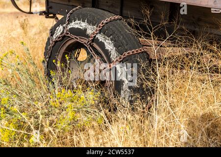 Metallschneeketten an einem abgenutzten Reifen an einem LKW in einem Grasfeld Stockfoto