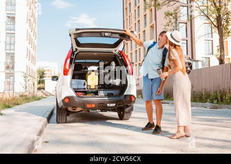 Paar sammeln für Road Trip. Putting Taschen auf Auto-Kofferraum Stockfoto