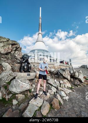 Hipster-Fotograf mit Vintage-Analogkamera macht Bilder auf Berggipfel mit dem Turm im Hintergrund. Stockfoto