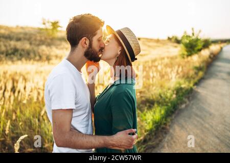 Glücklicher junger Mann und Frau lächeln und umarmen draußen bei Sonnenuntergang. Konzept von Menschen, Liebe und Lebensstil. Stockfoto