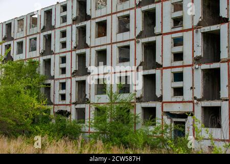 Ein verlassenes mehrstöckiges Gebäude steht inmitten eines grünen Feldes. Stockfoto