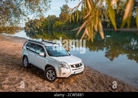 Blick auf das suv-Auto am Flussstrand bei Sonnenuntergang Stockfoto