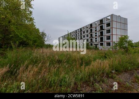 Ein verlassenes mehrstöckiges Gebäude steht inmitten eines grünen Feldes. Stockfoto