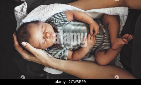 Foto der oberen Ansicht eines neugeborenen Babys, das auf ihm schläft Arme der Eltern Stockfoto