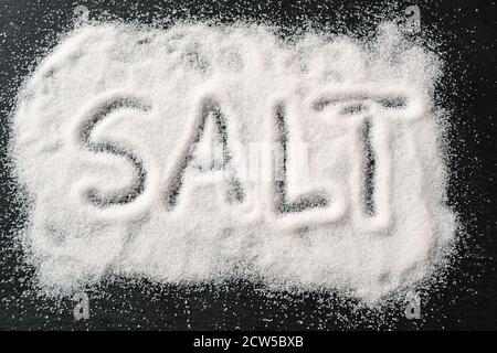 Wort SALZ in gegossenen Salzkristalle auf einem dunklen Schiefer geschrieben, hohe Winkel Ansicht von oben, ausgewählter Fokus Stockfoto