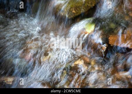 Abstrakt lange Exposition Waldbach Kaskadierung über bunte Steine und Blätter. Stockfoto