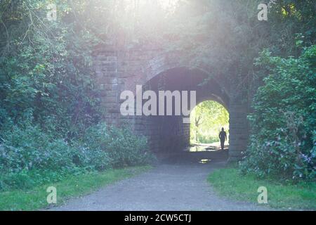 Licht am Ende des Tunnels - Standort des seit langem geschlossenen Molyneux Brow Railway Station, Clifton, England. Person im Tunnel, Silhouette Stockfoto