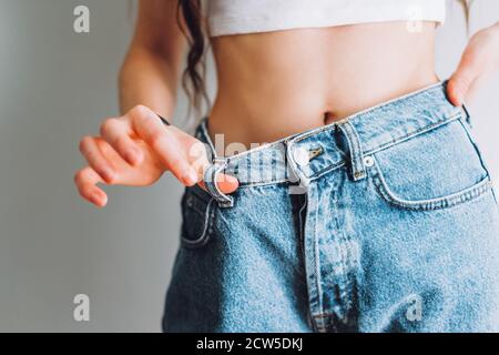 Frau hält Jeans in der Hand, zeigt eine dünne Taille Slim weiblichen Körper in großen Jeans Stockfoto