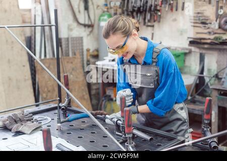 Frau in der Metallwerkstatt mit Werkzeug und Werkstück Stockfoto