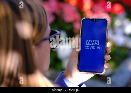 Stafford / UK - September 27 2020: NHS COVID-19 App Login-Bildschirm auf dem Smartphone gesehen, dass junge Mädchen ohne Maske in der Hand halten. Konzept für Tra Stockfoto