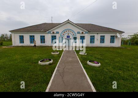 Weiß getünchtes Gebäude einer alten einstöckigen Schule im Dorf. Stockfoto