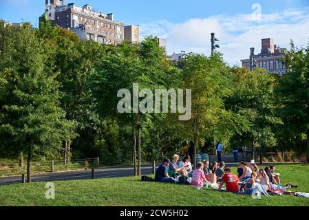 BROOKLYN, NY - SEPTEMBER 23 2020: Eine Gruppe von Menschen versammeln sich für ein Picknick, sitzen auf dem Rasen im Brooklyn Bridge Park, Brooklyn, NY Stockfoto