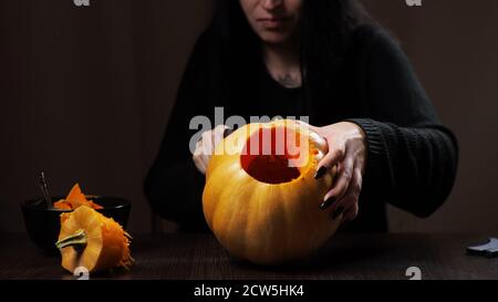 Junge Brünette Frau schnitzt einen Kürbis für Halloween Vorbereitung Stockfoto