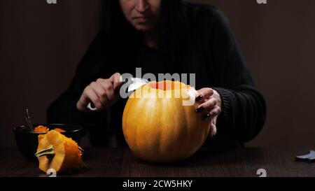 Junge Brünette Frau schnitzt einen Kürbis für Halloween Vorbereitung Stockfoto